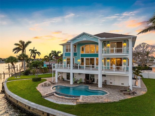 11000 8th St E, Treasure Island, FL 33706 - back of property at dusk featuring a balcony, stairway, a patio area, a fenced backyard, and a pool with connected hot tub