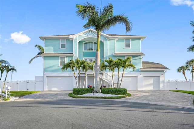 11000 8th St E, Treasure Island, FL 33706 - coastal inspired home with stairway, a gate, a garage, and driveway