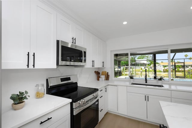 6508 Senegal Palm Way, Apollo Beach, FL 33572 - kitchen featuring stainless steel appliances, a sink, white cabinets, light stone countertops, and recessed lighting