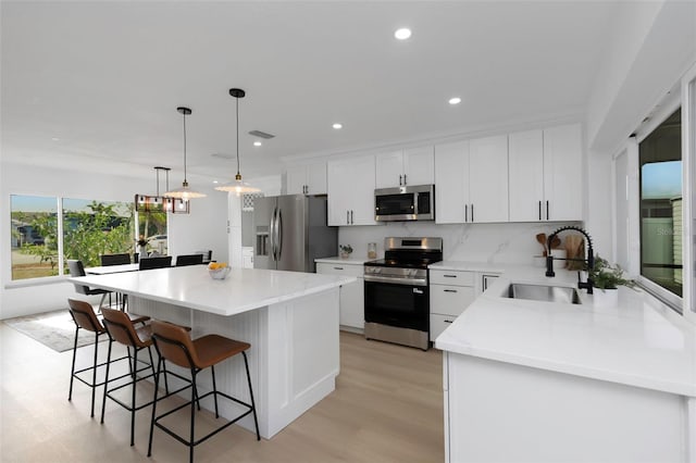 6508 Senegal Palm Way, Apollo Beach, FL 33572 - kitchen with stainless steel appliances, a breakfast bar, a sink, white cabinetry, and a kitchen island