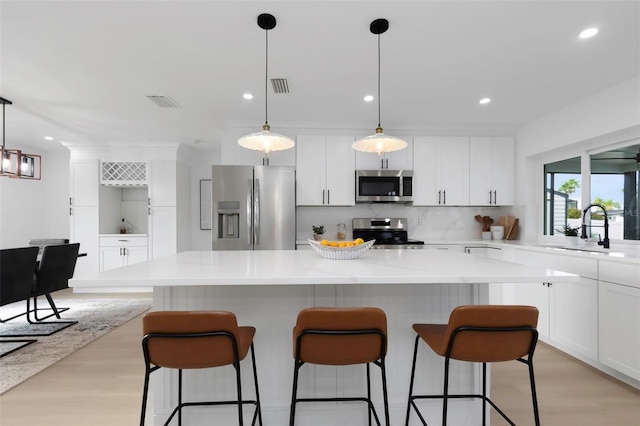 6508 Senegal Palm Way, Apollo Beach, FL 33572 - kitchen with appliances with stainless steel finishes, a sink, light wood-style flooring, backsplash, and white cabinets