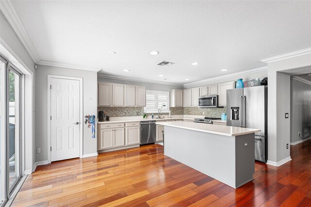 3351 Lintower Dr, Land O Lakes, FL 34638 - kitchen with stainless steel appliances, light countertops, decorative backsplash, light wood-type flooring, and crown molding
