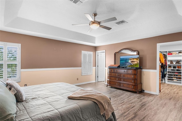 3351 Lintower Dr, Land O Lakes, FL 34638 - bedroom featuring a tray ceiling, wood finished floors, a walk in closet, and baseboards