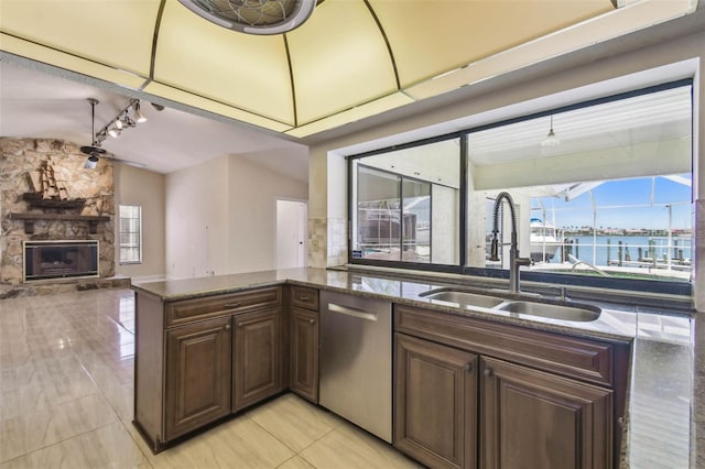 6322 Cocoa Ln, Apollo Beach, FL 33572 - kitchen featuring a sink, stainless steel dishwasher, light tile patterned floors, a fireplace, and dark stone counters