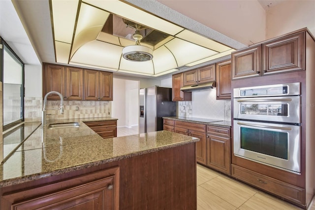 6322 Cocoa Ln, Apollo Beach, FL 33572 - kitchen featuring stainless steel appliances, a sink, a peninsula, dark stone countertops, and backsplash