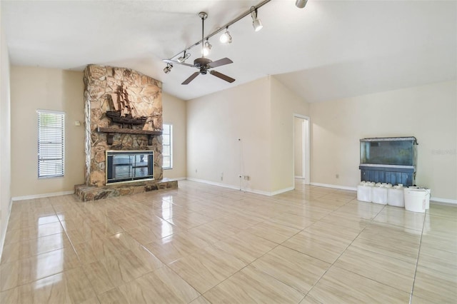 6322 Cocoa Ln, Apollo Beach, FL 33572 - unfurnished living room with vaulted ceiling, tile patterned floors, ceiling fan, a stone fireplace, and baseboards