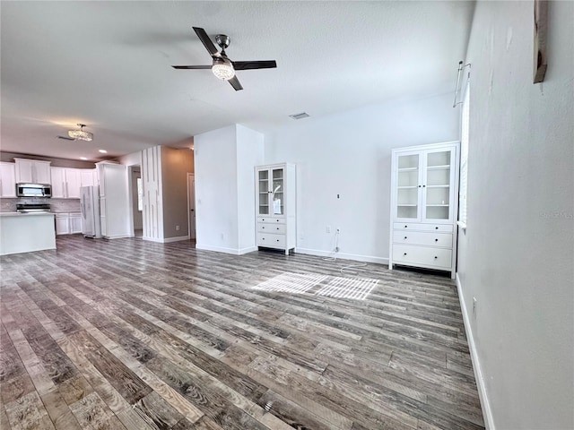 unfurnished living room featuring dark wood-style floors, a ceiling fan, and baseboards