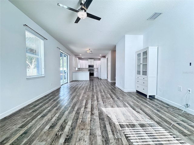 unfurnished living room featuring a ceiling fan, dark wood-style floors, and baseboards