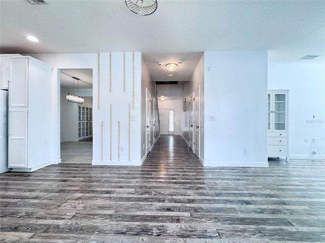 unfurnished living room featuring dark wood finished floors, a textured ceiling, and baseboards