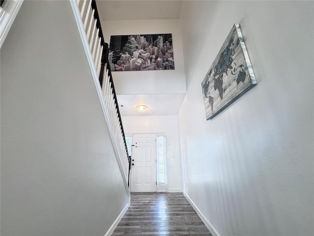 doorway to outside featuring dark wood-style flooring, baseboards, and stairs