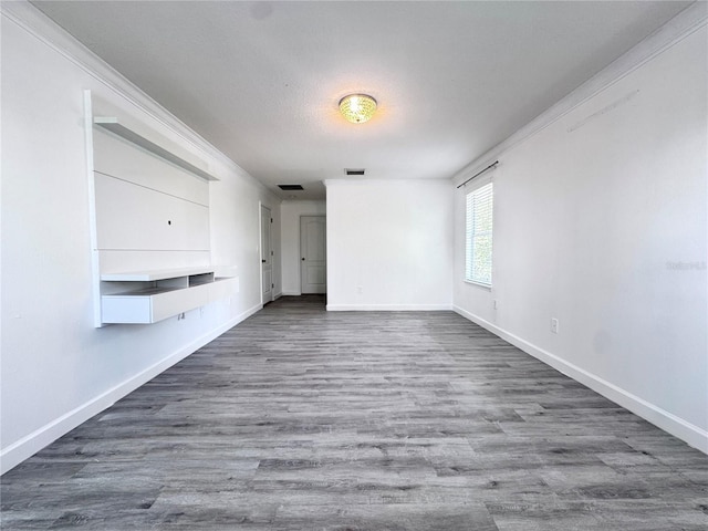 spare room with baseboards, wood finished floors, and ornamental molding