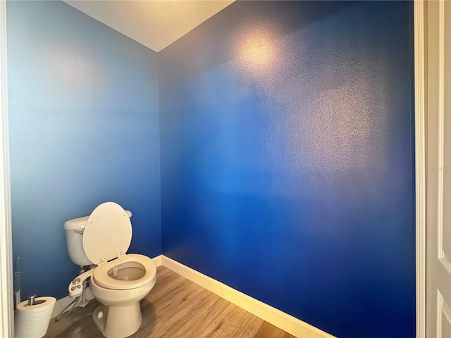 bathroom with baseboards, wood finished floors, and toilet