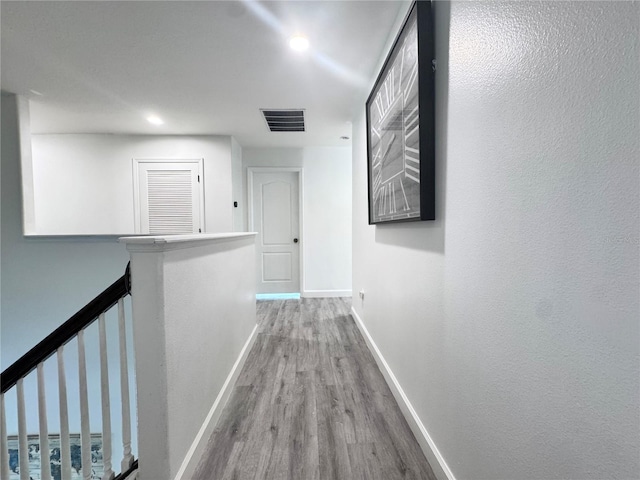 corridor featuring wood finished floors, an upstairs landing, baseboards, and recessed lighting