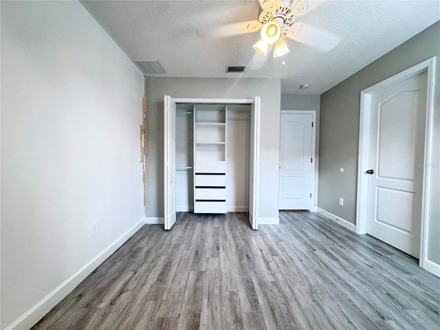 unfurnished bedroom featuring wood finished floors, a closet, baseboards, a textured ceiling, and a ceiling fan