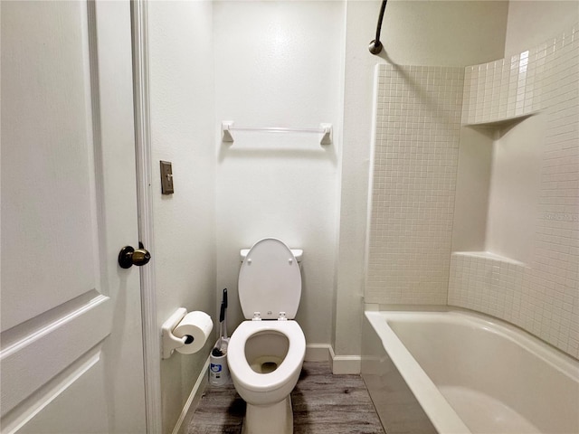 bathroom featuring wood finished floors, toilet,  shower combination, and baseboards