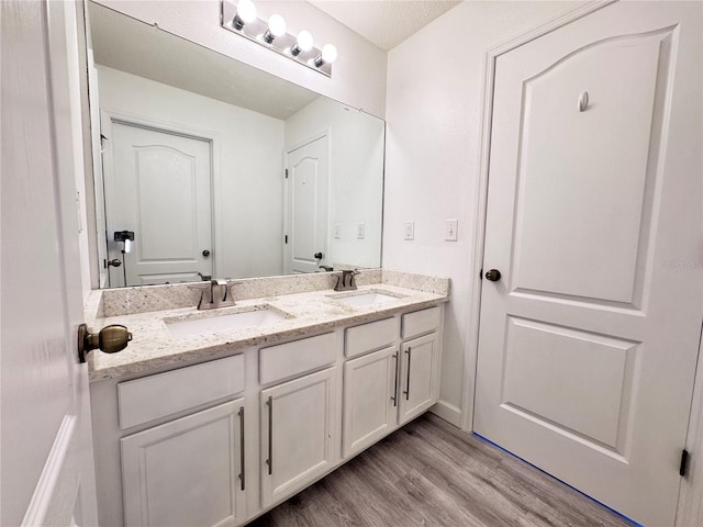 bathroom featuring wood finished floors, double vanity, and baseboards