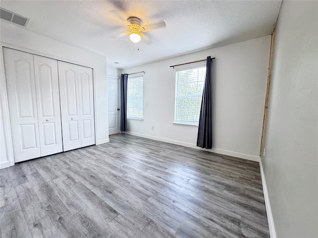unfurnished bedroom featuring baseboards, wood finished floors, a closet, a ceiling fan, and a textured ceiling