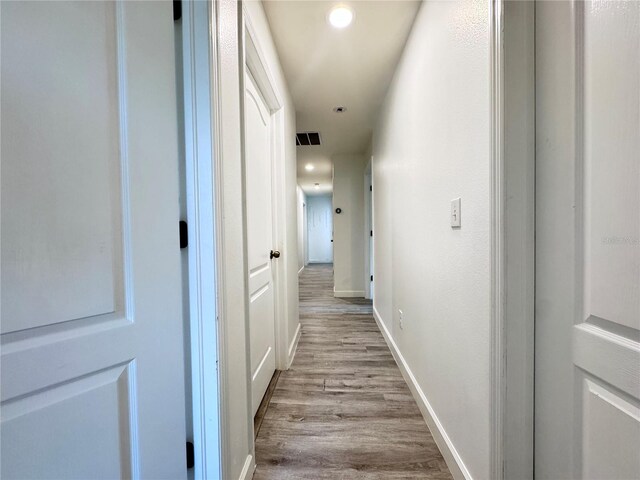 hallway featuring wood finished floors, recessed lighting, and baseboards
