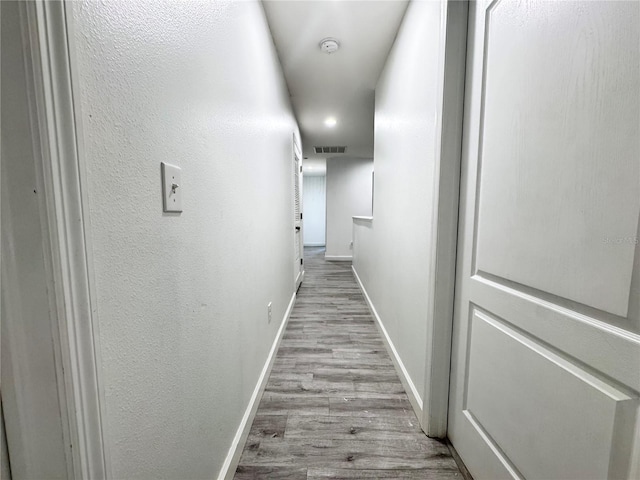 corridor featuring wood finished floors, baseboards, and recessed lighting