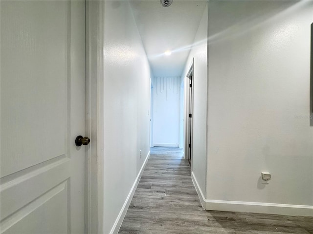 hallway featuring wood finished floors and baseboards