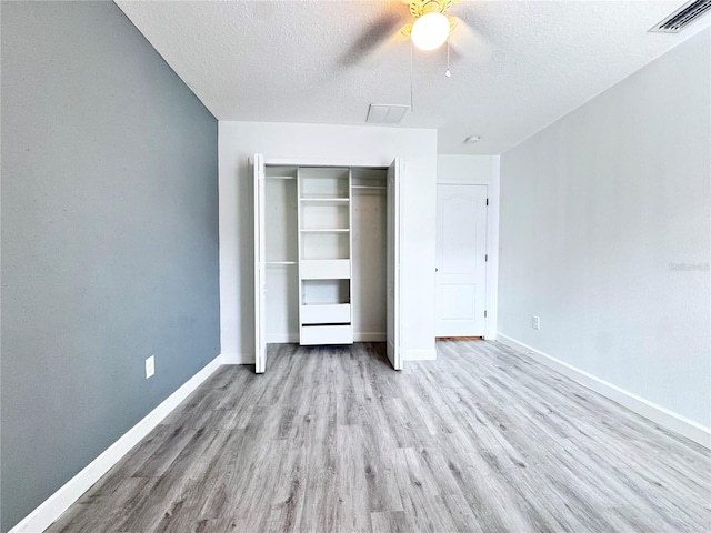 unfurnished bedroom featuring a textured ceiling, wood finished floors, a closet, baseboards, and ceiling fan