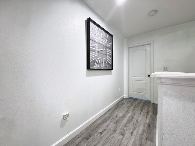 corridor featuring wood finished floors and baseboards