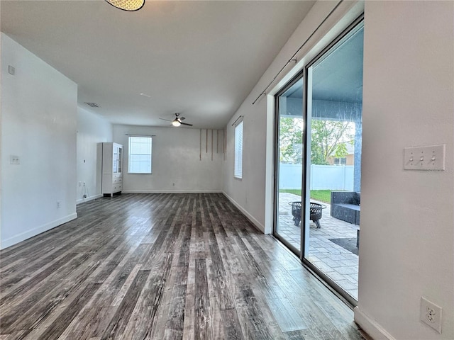 empty room featuring dark wood finished floors, a ceiling fan, and baseboards