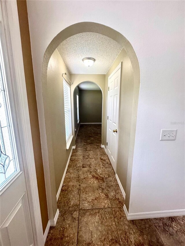 3181 Deltona Blvd, Spring Hill, FL 34606 - hall with arched walkways, plenty of natural light, a textured ceiling, and baseboards