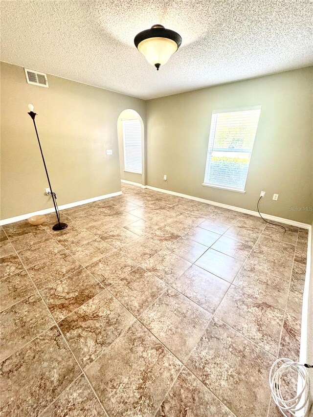 3181 Deltona Blvd, Spring Hill, FL 34606 - tiled spare room with arched walkways, a textured ceiling, and baseboards