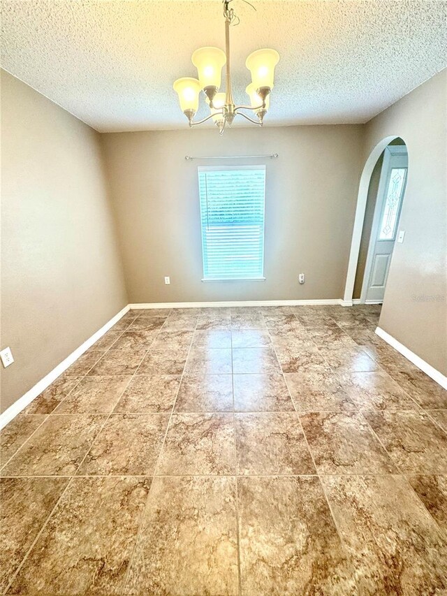3181 Deltona Blvd, Spring Hill, FL 34606 - unfurnished room featuring arched walkways, a chandelier, a textured ceiling, tile patterned floors, and baseboards