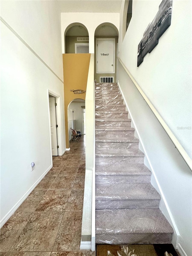 3181 Deltona Blvd, Spring Hill, FL 34606 - stairway featuring baseboards, a towering ceiling, and arched walkways