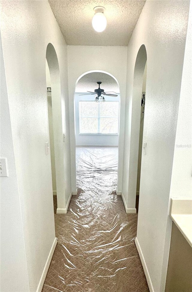 3181 Deltona Blvd, Spring Hill, FL 34606 - hallway with arched walkways, a textured ceiling, and baseboards