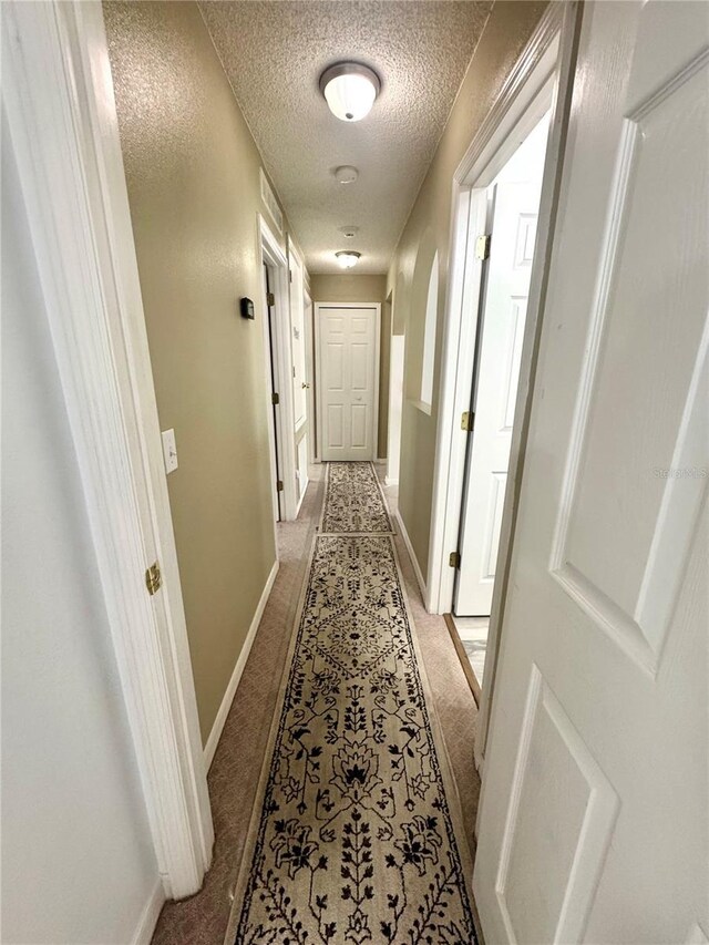 3181 Deltona Blvd, Spring Hill, FL 34606 - hallway featuring a textured ceiling, baseboards, and light carpet
