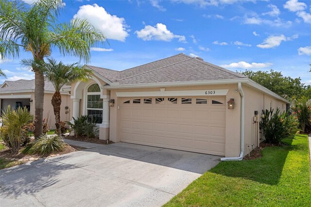6303 Gentle Ben Cir, Wesley Chapel, FL 33544 - view of front of house with a garage, stucco siding, concrete driveway, and a shingled roof