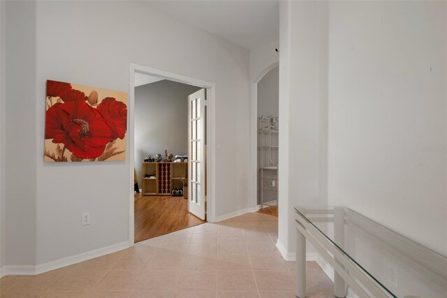 6303 Gentle Ben Cir, Wesley Chapel, FL 33544 - hallway featuring arched walkways, light tile patterned flooring, and baseboards