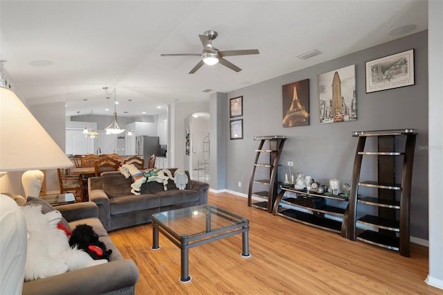 6303 Gentle Ben Cir, Wesley Chapel, FL 33544 - living room with arched walkways, a ceiling fan, light wood-style floors, and baseboards