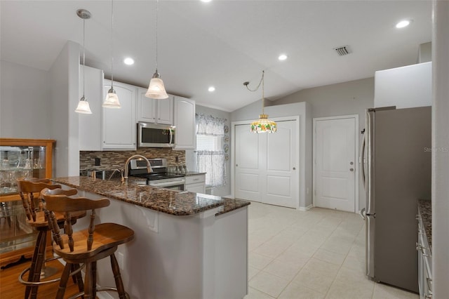 6303 Gentle Ben Cir, Wesley Chapel, FL 33544 - kitchen with stainless steel appliances, a peninsula, tasteful backsplash, dark stone counters, and lofted ceiling