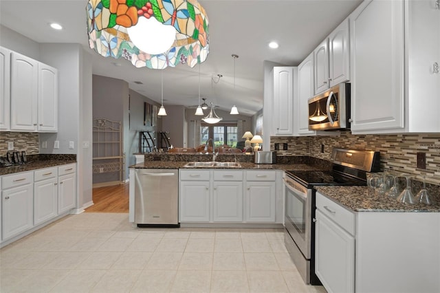 6303 Gentle Ben Cir, Wesley Chapel, FL 33544 - kitchen featuring appliances with stainless steel finishes, a sink, a peninsula, tasteful backsplash, and dark stone countertops