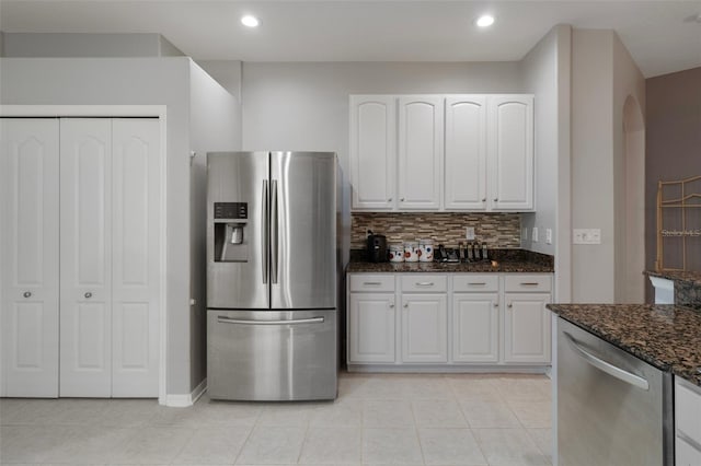 6303 Gentle Ben Cir, Wesley Chapel, FL 33544 - kitchen featuring appliances with stainless steel finishes, dark stone counters, decorative backsplash, light tile patterned flooring, and white cabinets