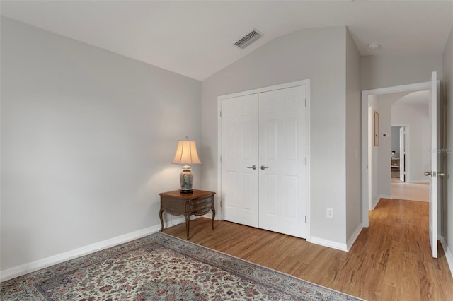 6303 Gentle Ben Cir, Wesley Chapel, FL 33544 - bedroom featuring light wood-type flooring, baseboards, arched walkways, lofted ceiling, and a closet