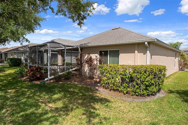 6303 Gentle Ben Cir, Wesley Chapel, FL 33544 - back of house featuring stucco siding, a yard, roof with shingles, and glass enclosure