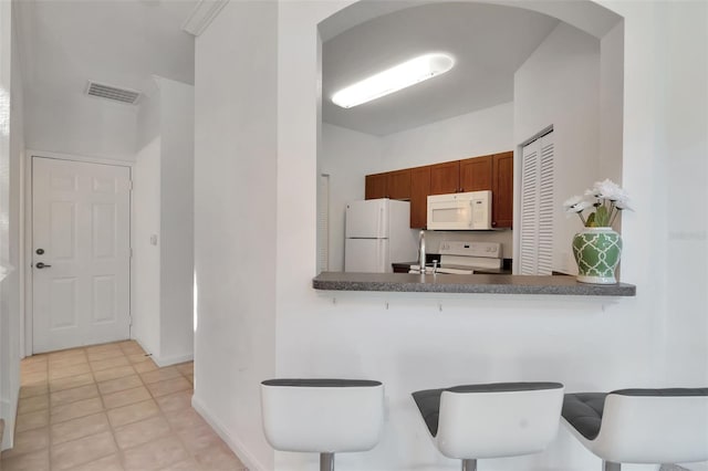 2173 Tuscany Trce Unit 8, Palm Harbor, FL 34683 - kitchen featuring white appliances, arched walkways, dark countertops, baseboards, and a breakfast bar