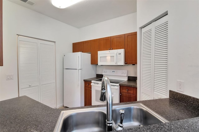 2173 Tuscany Trce Unit 8, Palm Harbor, FL 34683 - kitchen featuring white appliances, dark countertops, brown cabinets, and a sink