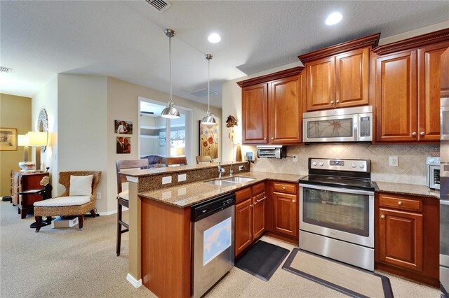 5646 Sunset Falls Dr, Apollo Beach, FL 33572 - kitchen featuring appliances with stainless steel finishes, a sink, a peninsula, a kitchen breakfast bar, and brown cabinetry