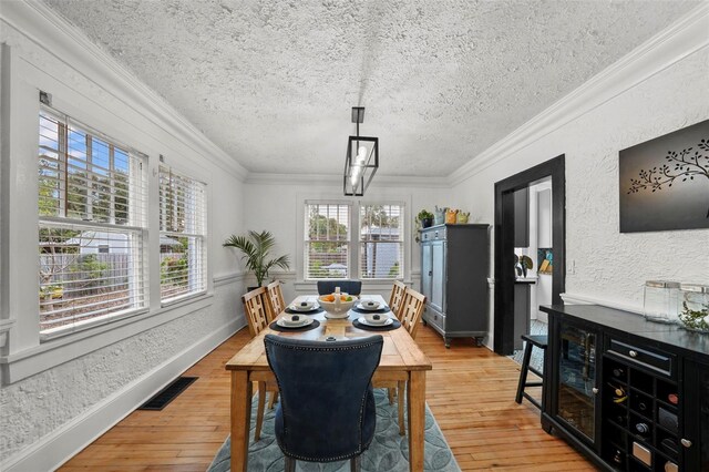 6251 4th Ave S, Saint Petersburg, FL 33707 - dining space featuring a textured ceiling, light wood-style flooring, crown molding, and a textured wall