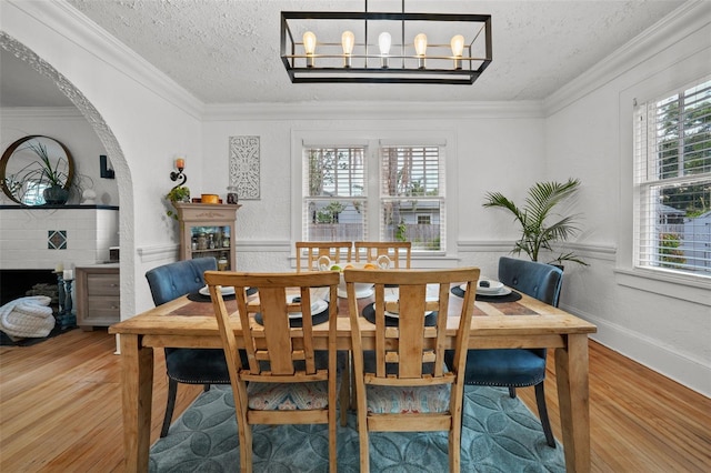 6251 4th Ave S, Saint Petersburg, FL 33707 - dining space featuring a fireplace, plenty of natural light, wood finished floors, a textured ceiling, and ornamental molding