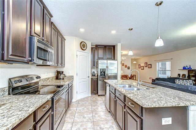 2723 Garden Falls Dr, Brandon, FL 33511 - kitchen featuring stainless steel appliances, a sink, dark brown cabinetry, a center island with sink, and a textured ceiling