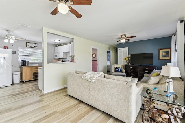 13920 Berkowitz Ave, Hudson, FL 34667 - living room featuring a ceiling fan, light wood-style flooring, and baseboards