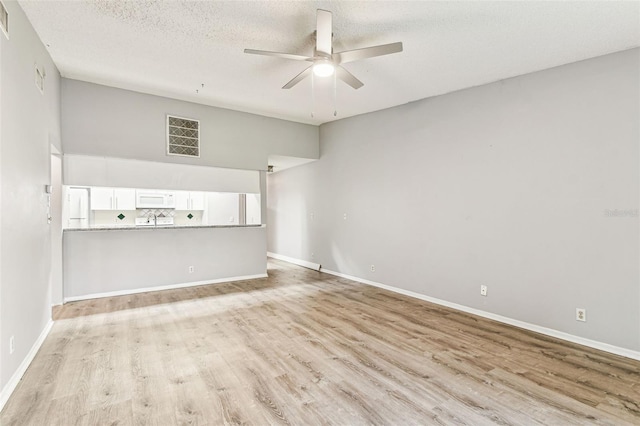 39650 US Highway 19 N Unit 143, Tarpon Springs, FL 34689 - unfurnished living room featuring light wood-type flooring, a ceiling fan, baseboards, and a textured ceiling