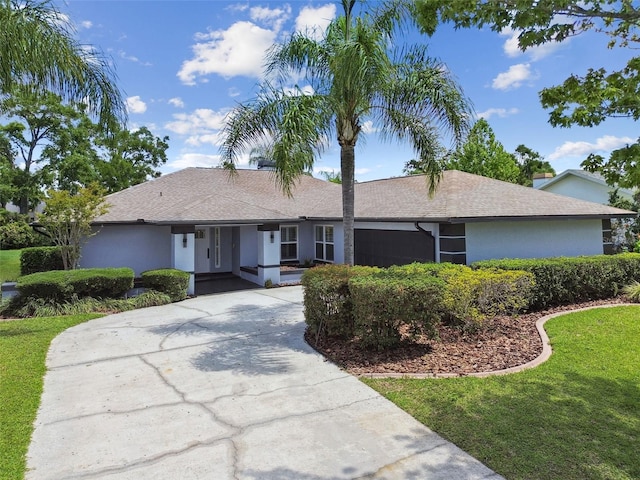 14170 Fennsbury Dr, Tampa, FL 33624 - ranch-style home featuring a front yard, concrete driveway, stucco siding, and roof with shingles